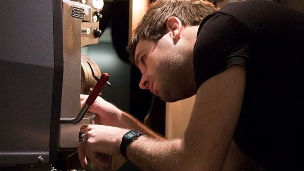 Ally McCrum laces a 70mm film print on a film projector. © Jenny Leask, 2024 EIFF 